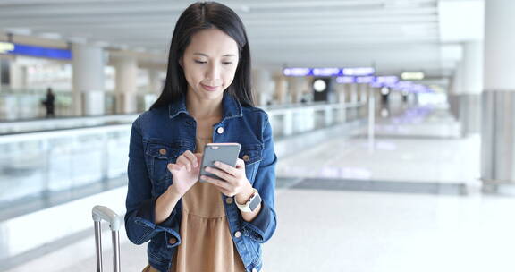 女子在香港机场玩手机等待登机