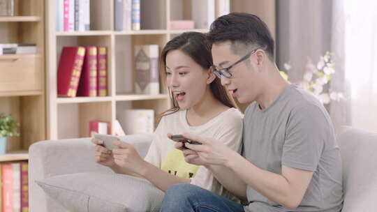 年轻夫妇在家中一起使用手机打游戏网购