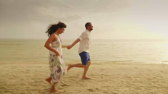 夫妇在沙滩上一起奔跑视频素材模板下载