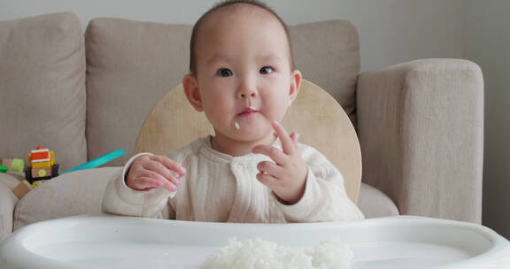 可爱亚洲小孩用手抓白米饭吃