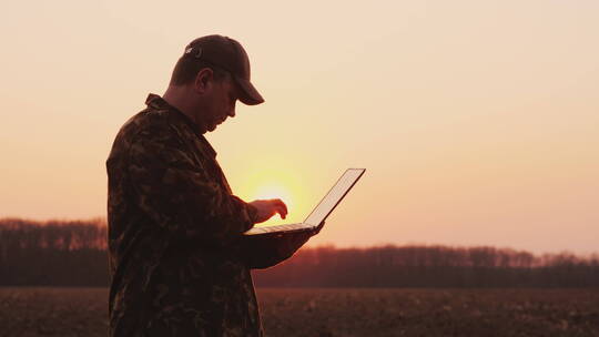 农民在田里使用笔记本电脑
