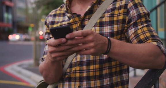 白人男性微笑着在街上使用手机