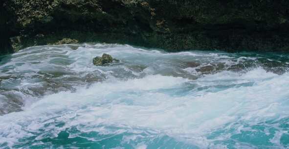 波浪撞击岩石，在悬崖下形成白水