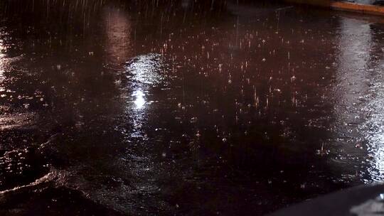 夜晚雨天街边小区路口地面溅起雨水路面积水