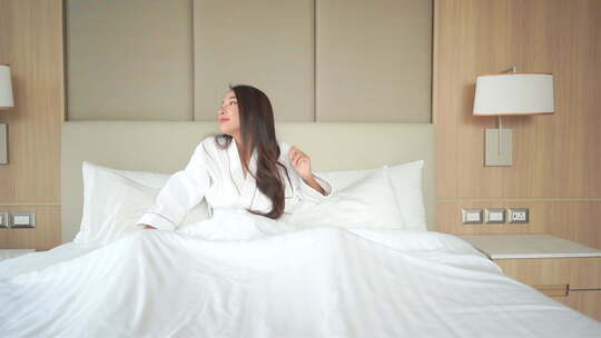 美丽的亚洲女人醒来在床上和伸展手臂SLO