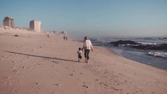 母亲和儿子手牵手在海滩上慢跑