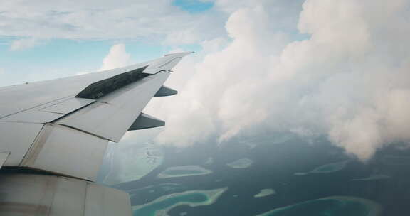 飞机机翼的慢动作，从飞机照明中看到云和岛