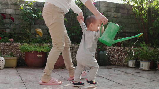 刚学会走路的小宝宝在花园里浇水视频素材模板下载