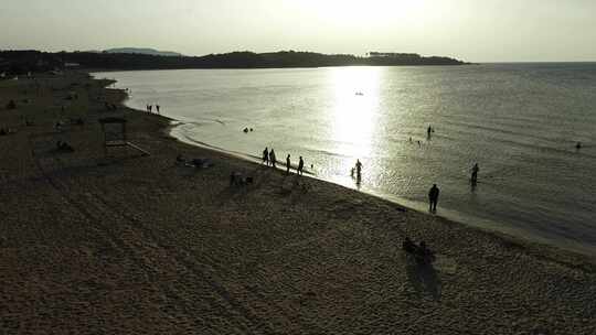 人们坐在沙滩上晒日光浴在海里游泳