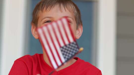 男孩微笑着挥舞着一面小美国国旗