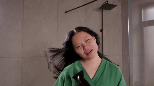 快乐成熟的亚洲女人用吹风机造型头发和唱歌视频素材模板下载