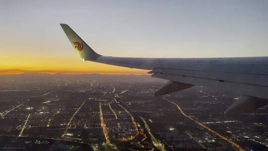 飞行中的飞机窗外日落和城市夜景景色