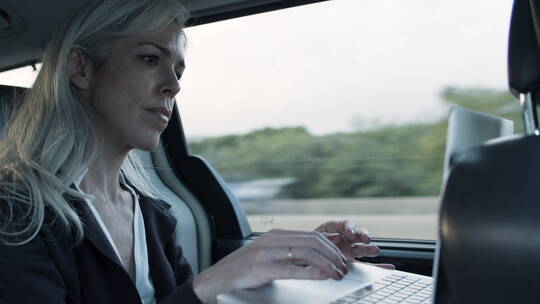在汽车里使用笔记本电脑的女人