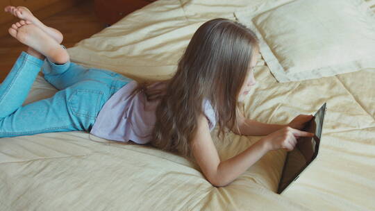 女孩在床上使用平板电脑视频素材模板下载