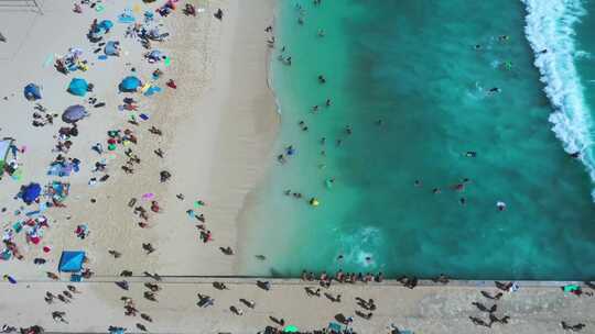 4k航拍海边的海浪和沙滩上度假的人们