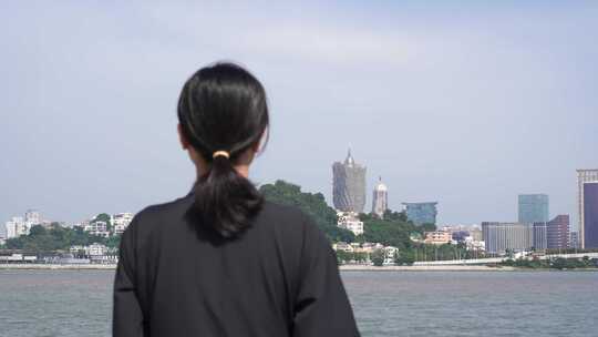 游客站在海岸边看澳门城市风景观望澳门塔