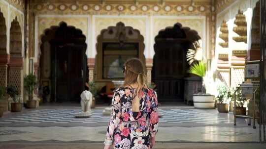 穿着太阳裙的女人走在印度宫殿的台阶上