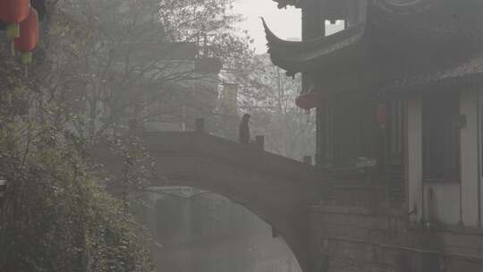 在中式拱桥上行走的男子