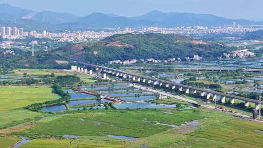 高铁行驶在绿意盎然的山间田野上