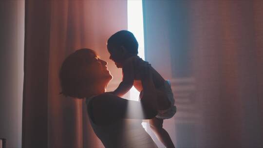 母亲和婴儿在玩耍在窗户旁视频素材模板下载