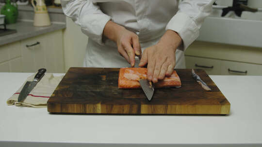 明星厨师在木板上将新鲜鲑鱼片切成薄片，特