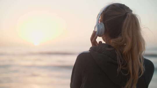 在海边戴耳机听音乐的女生背影