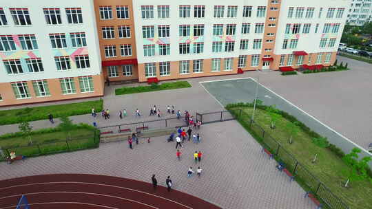 鸟瞰走在运动场上的学童校园，学校足球场