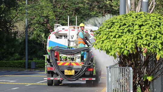 环卫工操作洒水车进行街道喷灌作业