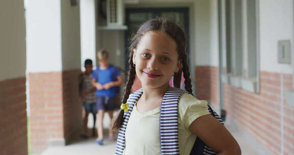 快乐的女孩站在学校走廊上