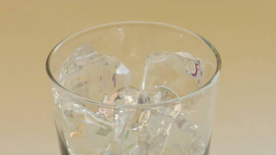 将饮料倒进有透明冰块的玻璃杯中