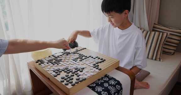 可爱的男孩在窗边下围棋