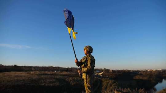 身着军装的士兵站在山上，举起乌克兰国旗乌