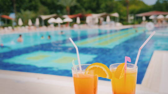 摆在泳池前的两杯橙汁