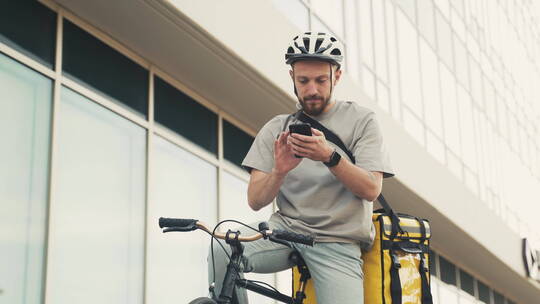 送餐员在自行车上看手机视频素材模板下载