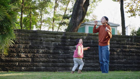 快乐小朋友在院子里和妈妈一起玩耍吹泡泡