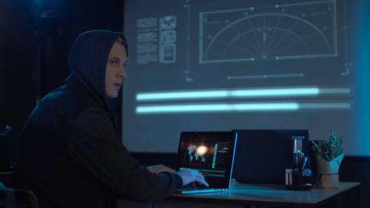 一个背着兜帽的黑客坐在笔记本电脑前