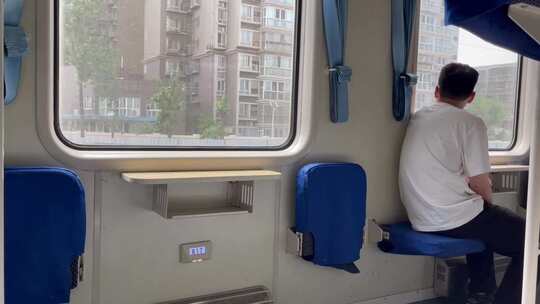 行驶中火车窗外的城市座椅上的背影