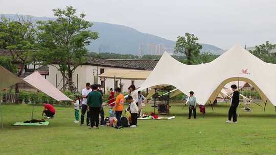 户外草坪上人们搭建帐篷露营的场景