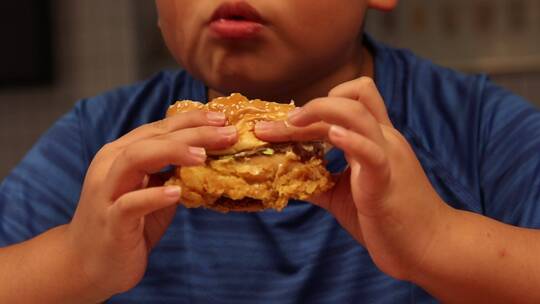 小孩在肯德基大口吃汉堡视频素材模板下载