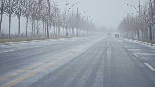 冬天车辆行驶在路上初雪在路上飞舞