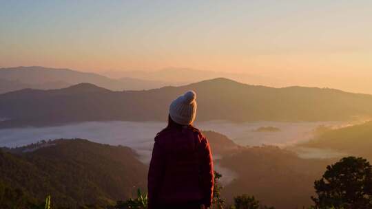 年轻的女性旅行者在山上看日出和雾海