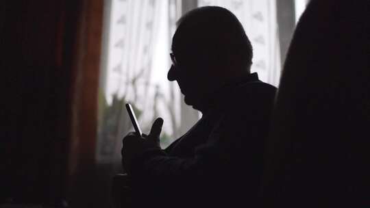 窗边有智能手机的老人