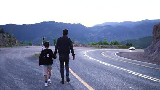 父亲牵着儿子在公路散步