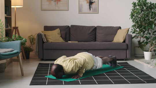 家庭锻炼时，老年黑人在地板上做俯卧撑视频素材模板下载