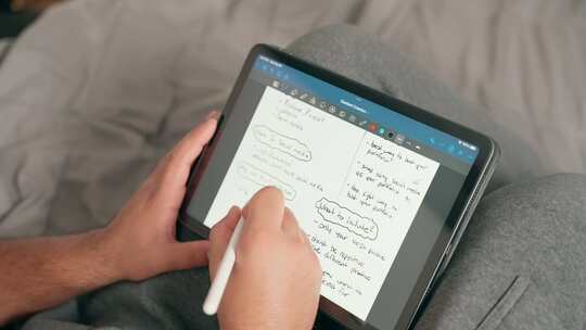 内容创作者、学生或自由职业者在iPad桌子上做笔记和数字规划的特写镜头