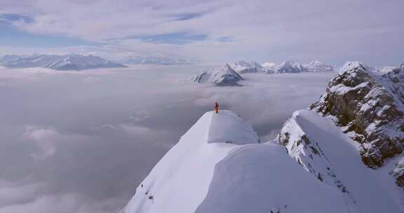 航拍环绕登顶雪山者，山间有白雪云海