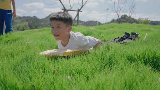 阳光下小朋友在草地上滑草玩耍