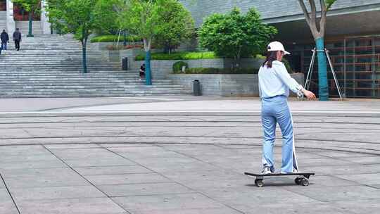 一名年轻美少女在公园广场独自一人练习滑板