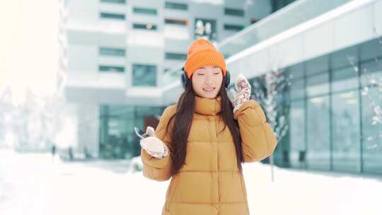 年轻美丽的亚洲女人在冬天下雪天听耳机里的