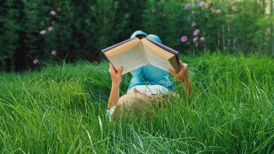 女孩在绿色草地上看书